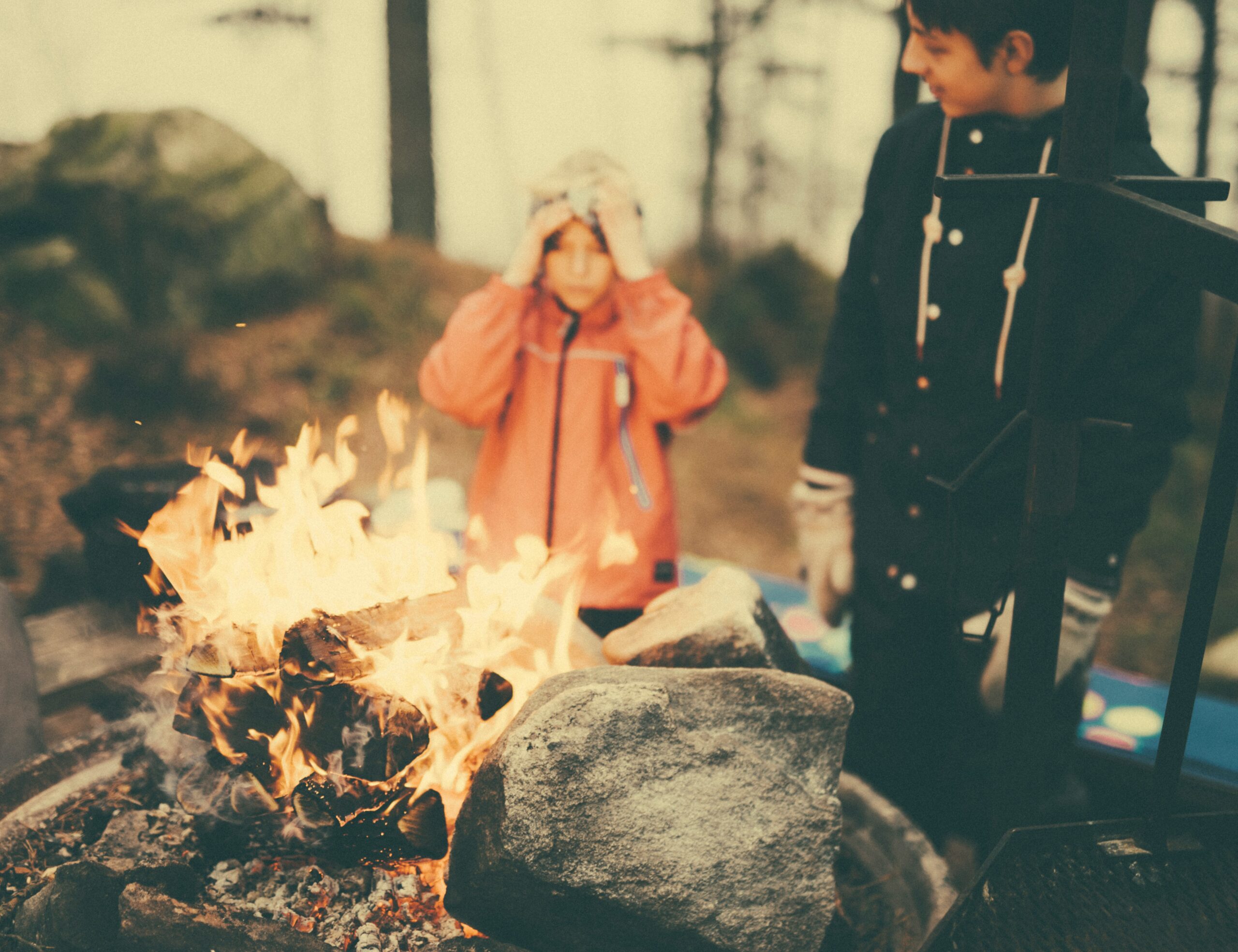 man in black sweatshirt standing in front of fire place surrounded by rocks during daytime